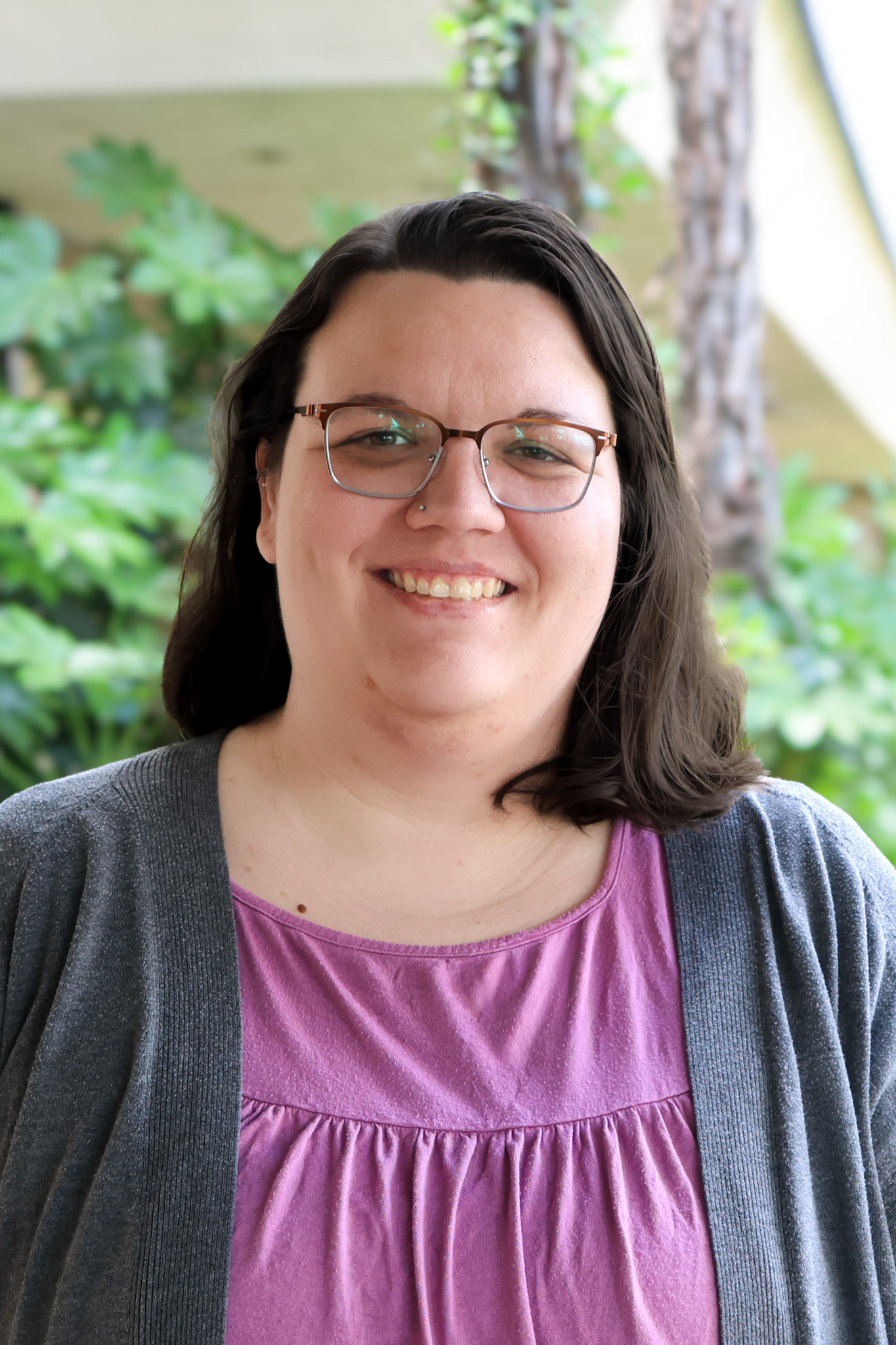 Smiling woman in a pink top and gray cardigan smiling