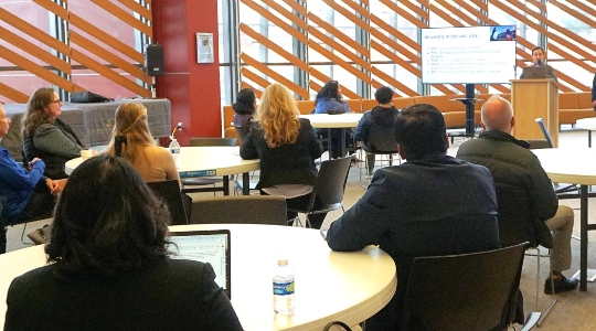 Faculty listening to speaker at podium