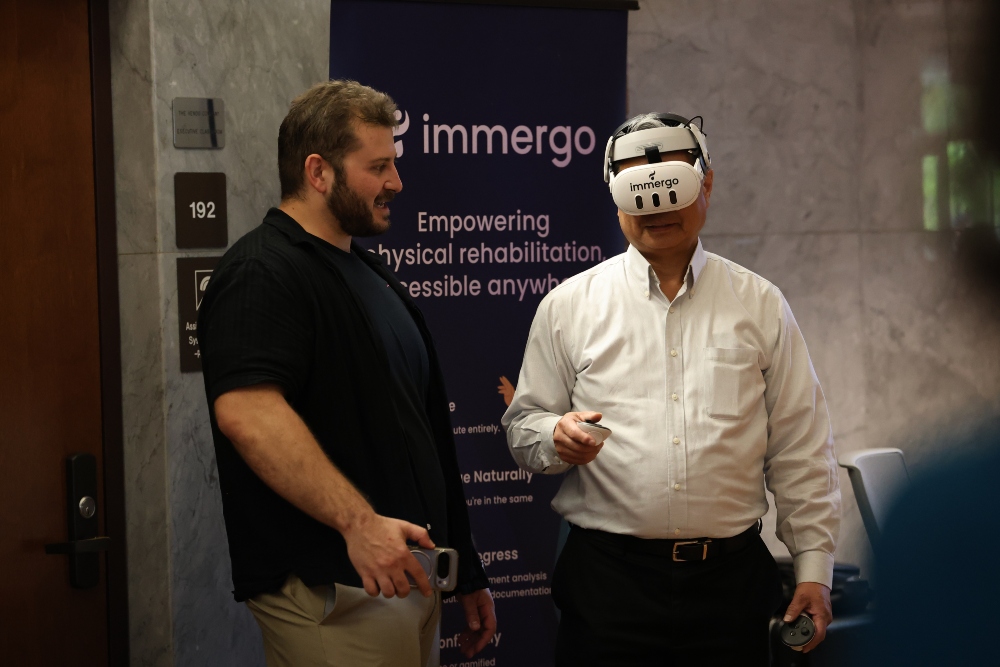 Person tries out immergo virtual headset while another person stands nearby