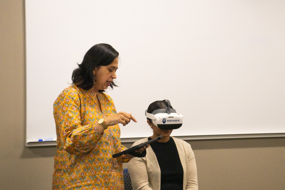 Student wears virtual reality headset as professor stands nearby