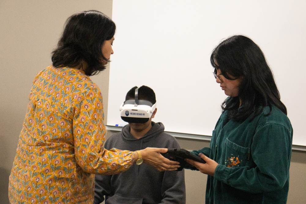 Student wears virtual reality headset as professor and another student stand nearby