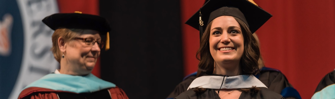 Student in graduation gown smiling 