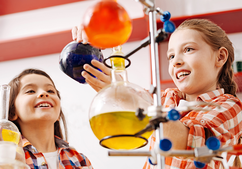 Two  school-aged girls are participating in a science experiment. 