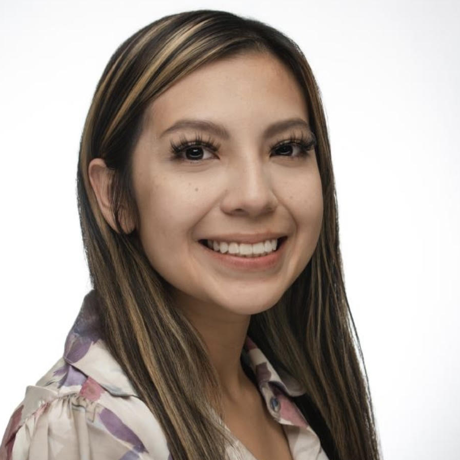 Headshot of a woman with brunette hair and a light highlight. 