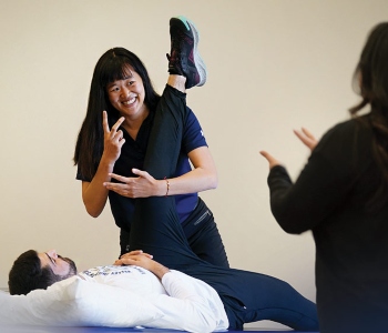 Student helps client with physical therapy stretches