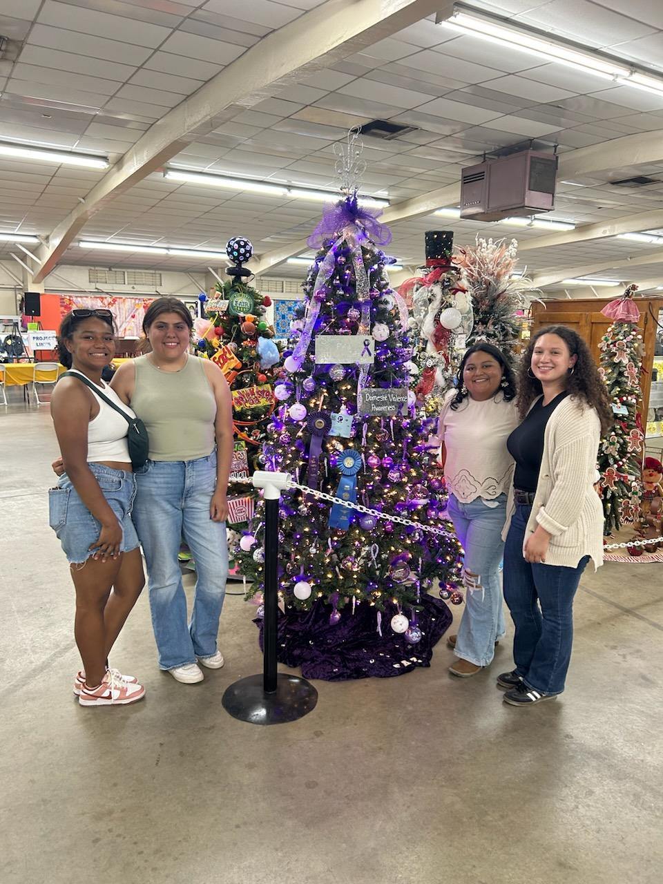 Sigma Alpha Zeta members next to domestic violence awareness tree with first place and best in show ribbons.